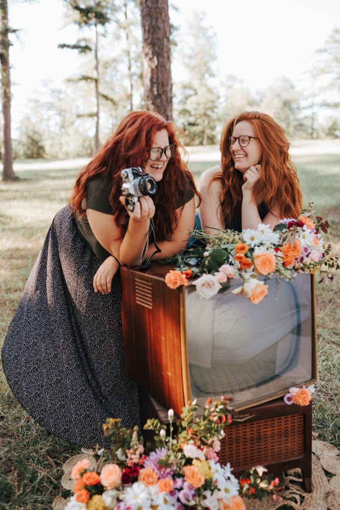 Two red headed best friends laughing and holding a camera. Taken at a photography workshop in Columbus Georgia. 
