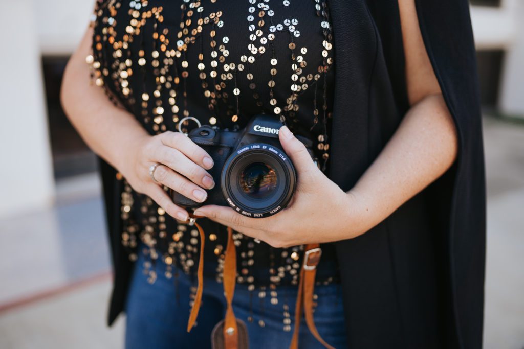 Close up image of a photographer holding her camera near her waist.