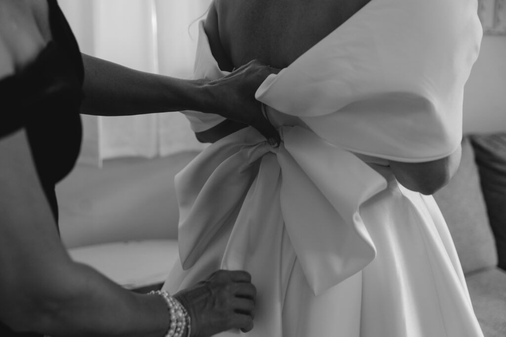 Close up of the Mother of bride's hands as she helps bride get zipped into her wedding dress